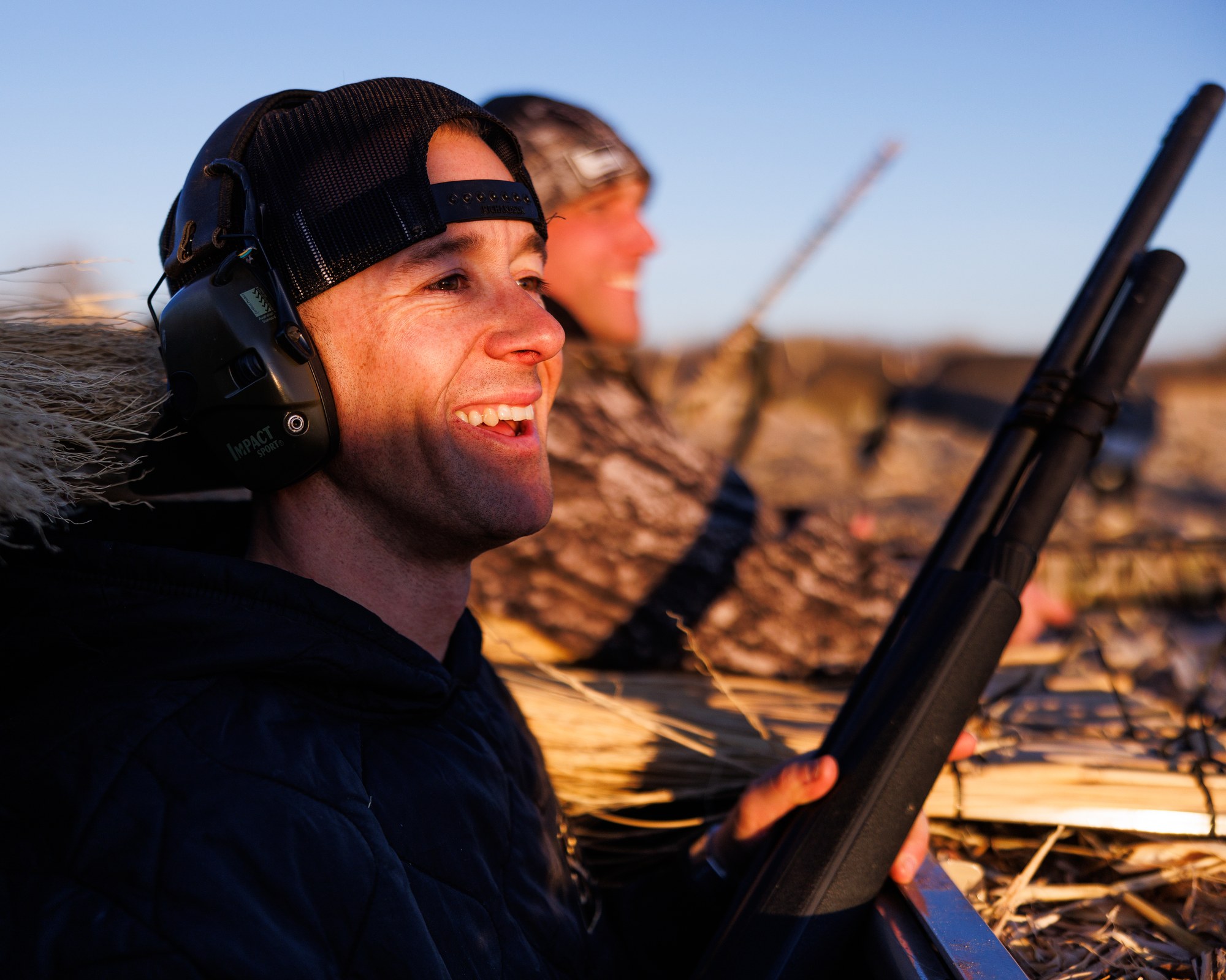 Veteran smiling in a duck blind at sunrise, holding a shotgun during a Darby's Warrior Support hunting outing